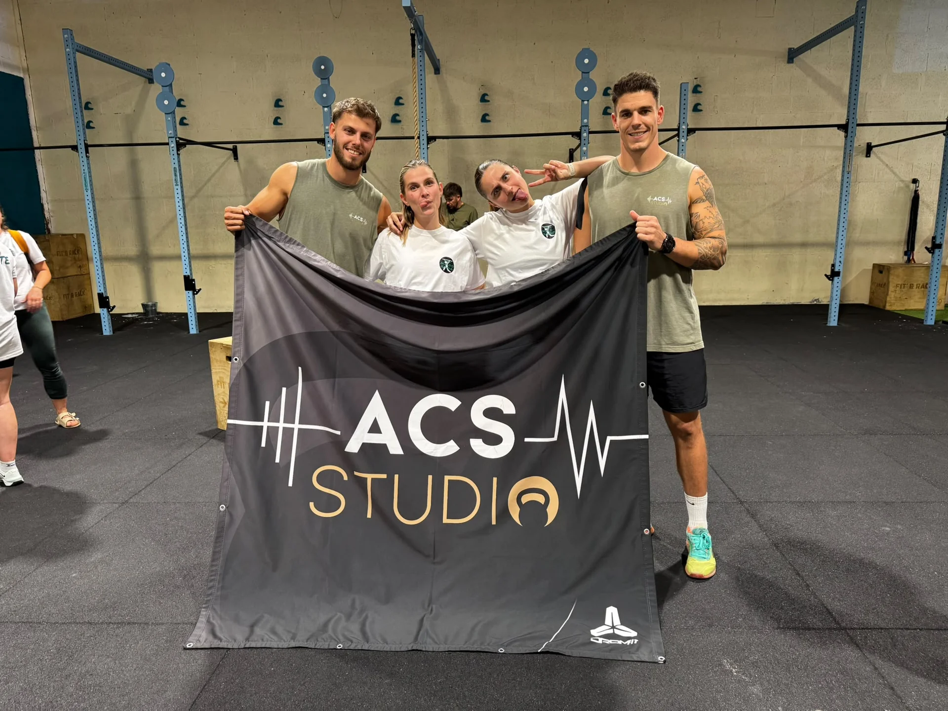 Un groupe présente une bannière ACS Studio dans un gymnase
